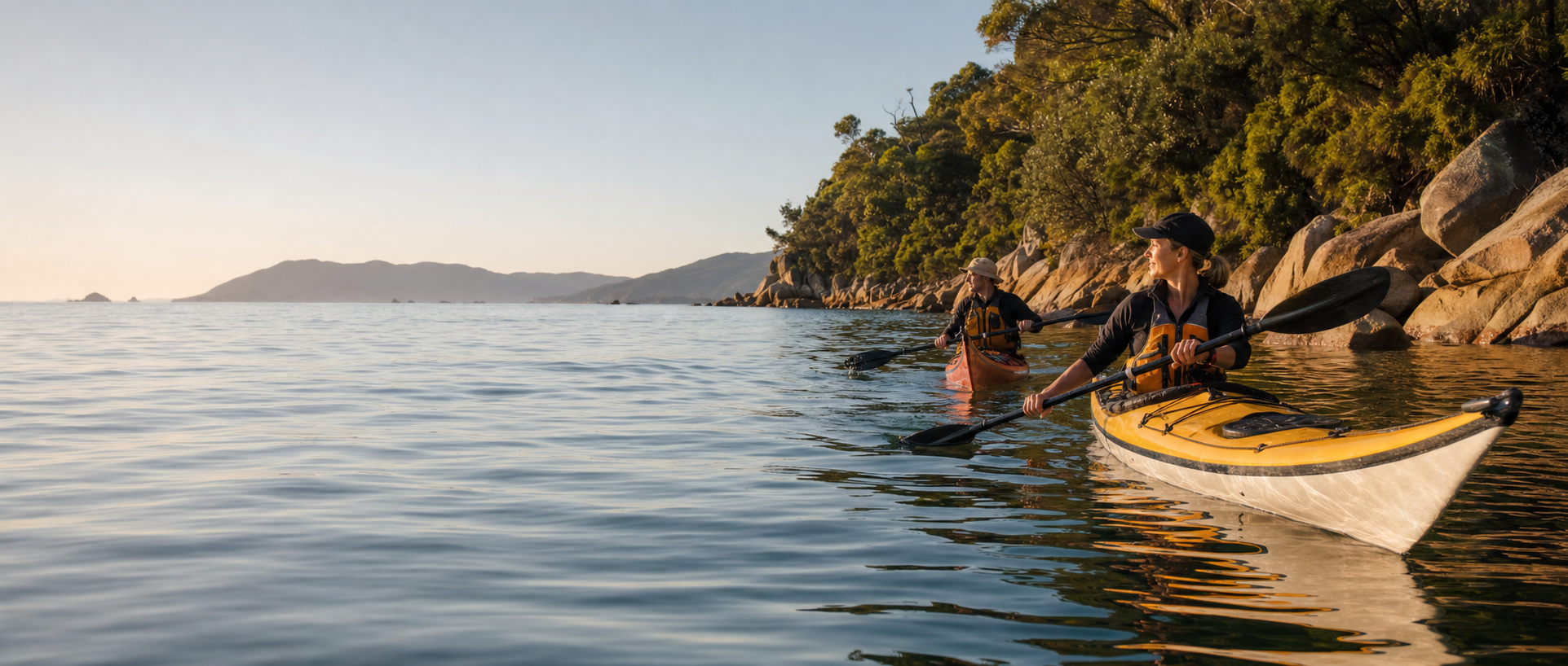 Two sea kayakers paddling beside the Tasman coast